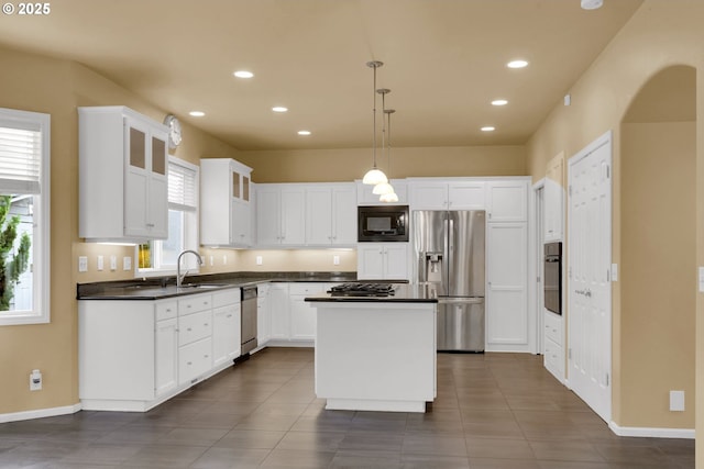 kitchen featuring decorative light fixtures, a center island, black appliances, plenty of natural light, and white cabinets