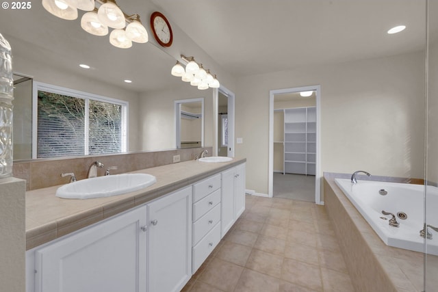 bathroom featuring tiled tub, vanity, and tile patterned flooring