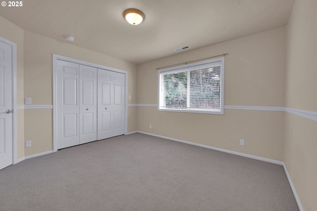 unfurnished bedroom with light colored carpet and a closet