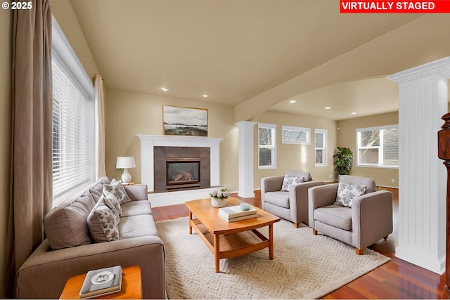 living room with ornate columns, a tile fireplace, and hardwood / wood-style floors