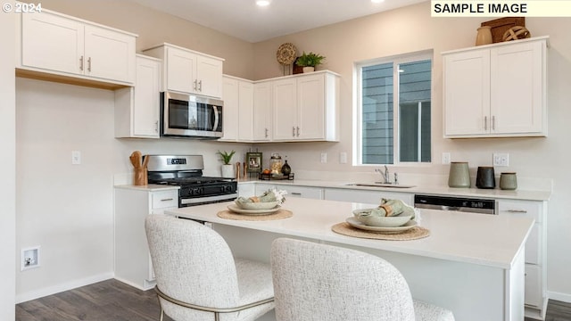 kitchen featuring appliances with stainless steel finishes, dark hardwood / wood-style floors, white cabinetry, sink, and a center island