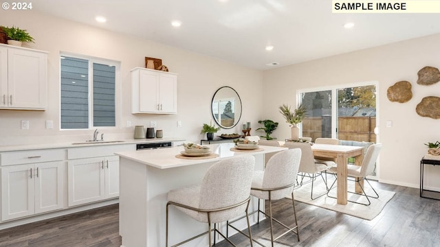 kitchen with dark hardwood / wood-style floors, sink, dishwashing machine, white cabinets, and a center island