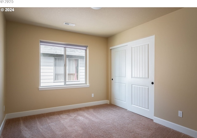 unfurnished bedroom with a closet and light carpet