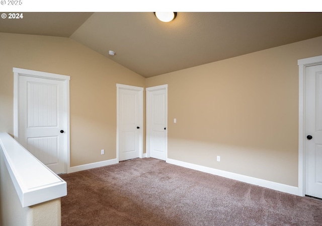 unfurnished bedroom with vaulted ceiling and carpet