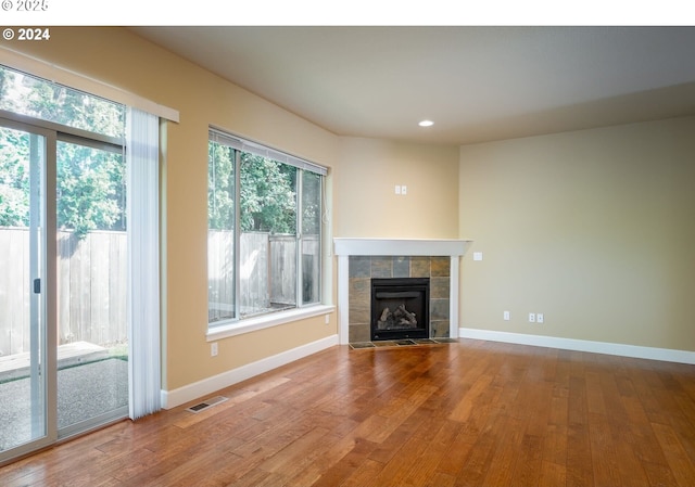 unfurnished living room with a tile fireplace and hardwood / wood-style floors