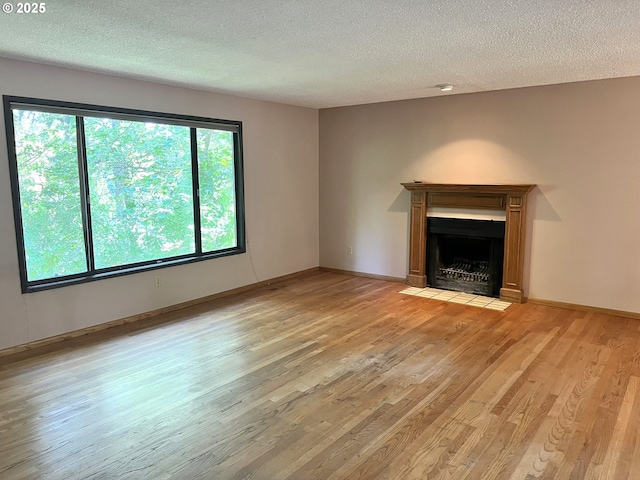 16042 Cornell St, Lake Oswego, OR 97034 - unfurnished living room featuring light wood-type flooring, a textured ceiling, and a fireplace with flush hearth