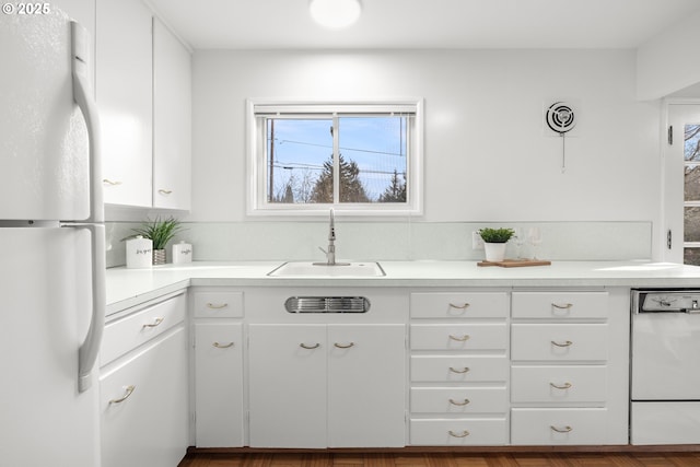 kitchen with freestanding refrigerator, white cabinetry, a sink, and dishwashing machine