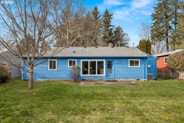 rear view of property featuring a shingled roof, cooling unit, fence, and a lawn