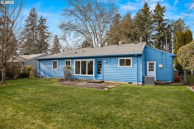 rear view of property featuring central AC unit, a shingled roof, fence, a lawn, and a patio area