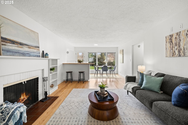 living room with a textured ceiling, a fireplace, wood finished floors, and baseboards