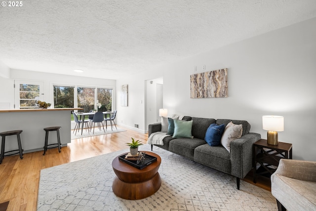 living room with a textured ceiling, baseboards, and wood finished floors