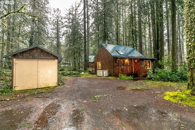 view of side of property featuring metal roof, a standing seam roof, a wooden deck, a shed, and an outdoor structure