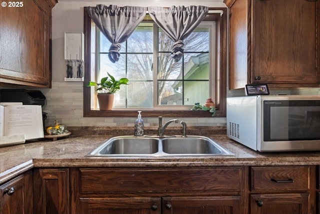 kitchen featuring tasteful backsplash, stainless steel microwave, and a sink