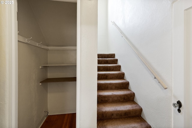 stairway featuring wood finished floors, baseboards, and vaulted ceiling
