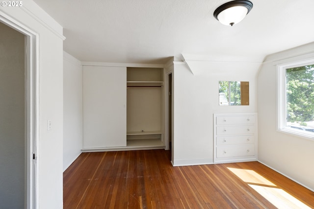 unfurnished bedroom with hardwood / wood-style flooring, a closet, and baseboards