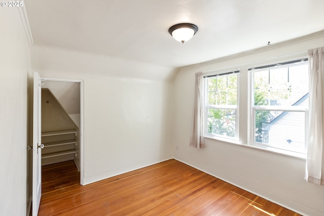 spare room with light wood finished floors and vaulted ceiling