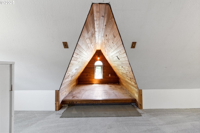 bonus room with wooden walls, carpet flooring, and vaulted ceiling