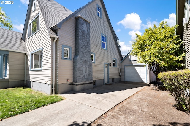 view of side of property featuring an outdoor structure and concrete driveway