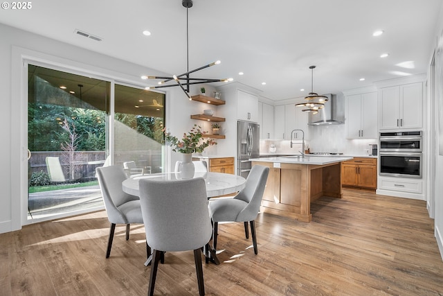 dining area featuring sink, a chandelier, and light hardwood / wood-style floors