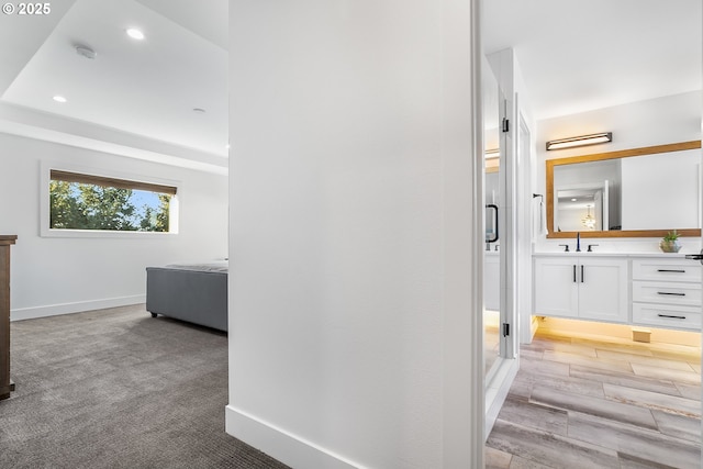 hallway with sink and light colored carpet