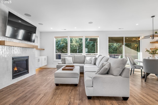 living room with a tile fireplace, a healthy amount of sunlight, and light wood-type flooring