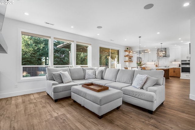 living room with hardwood / wood-style flooring, a healthy amount of sunlight, a chandelier, and sink