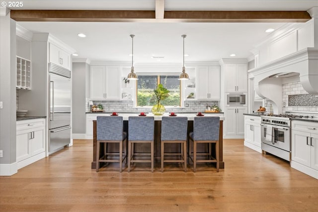 4015 NE 38th Ave, Portland, OR 97212 - kitchen featuring built in appliances, white cabinets, a breakfast bar, recessed lighting, and decorative backsplash