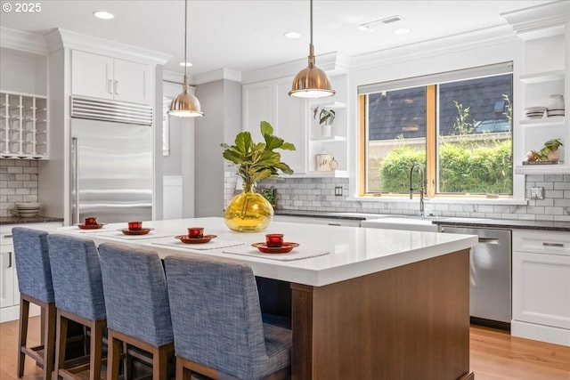 4015 NE 38th Ave, Portland, OR 97212 - kitchen featuring appliances with stainless steel finishes, tasteful backsplash, a kitchen island, ornamental molding, and white cabinetry