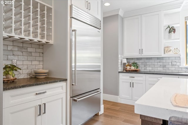 4015 NE 38th Ave, Portland, OR 97212 - kitchen with built in refrigerator, backsplash, white cabinetry, light wood-style flooring, and dark stone counters