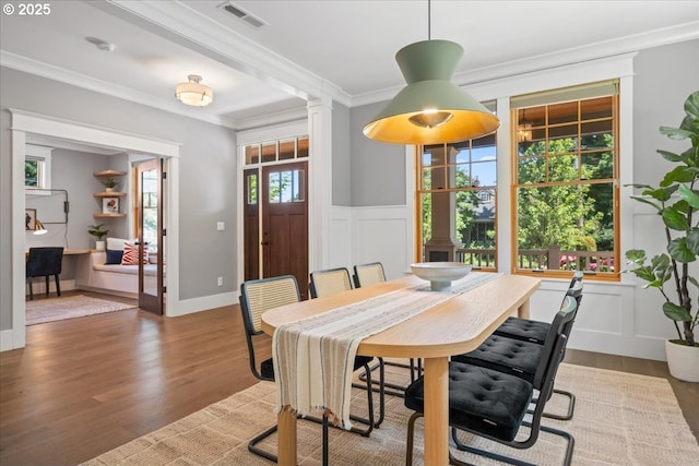 4015 NE 38th Ave, Portland, OR 97212 - dining space with crown molding, wood finished floors, a decorative wall, a wainscoted wall, and ornate columns