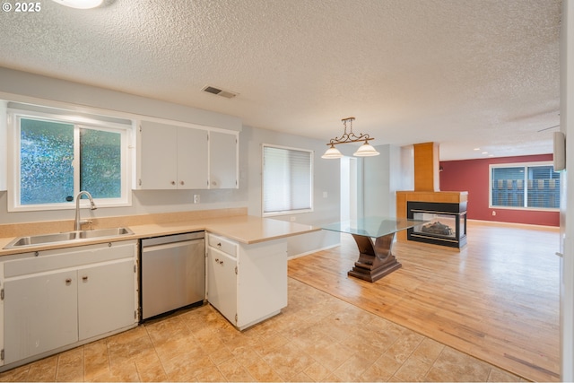446 44th Ave, Salem, OR 97317 - kitchen with stainless steel dishwasher, a sink, a multi sided fireplace, a peninsula, and a textured ceiling