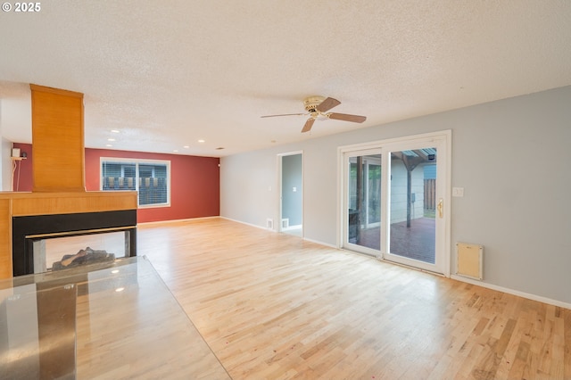 446 44th Ave, Salem, OR 97317 - unfurnished living room featuring wood finished floors, a textured ceiling, a multi sided fireplace, ceiling fan, and baseboards
