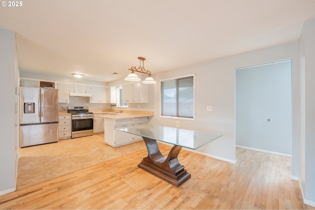 446 44th Ave, Salem, OR 97317 - kitchen with stainless steel appliances, light countertops, a peninsula, light wood-style floors, and baseboards