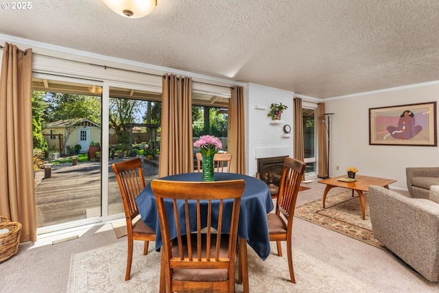 dining area with a glass covered fireplace, ornamental molding, light carpet, and a textured ceiling