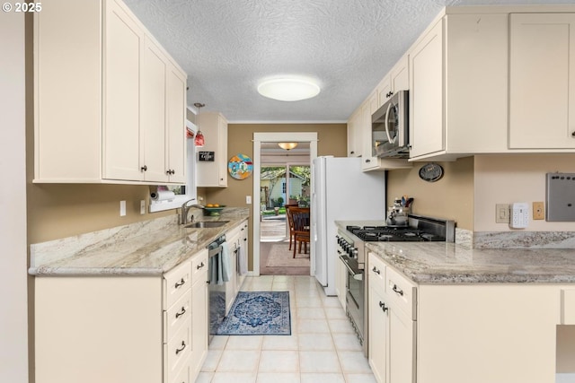 kitchen featuring white cabinets, light stone counters, a sink, stainless steel appliances, and light tile patterned floors