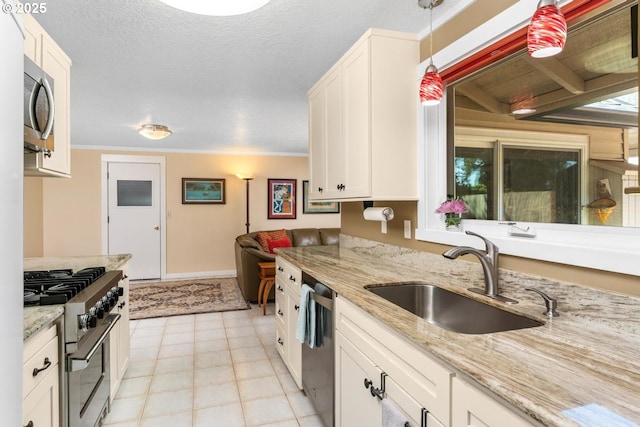 kitchen featuring white cabinets, light stone counters, a sink, stainless steel appliances, and baseboards
