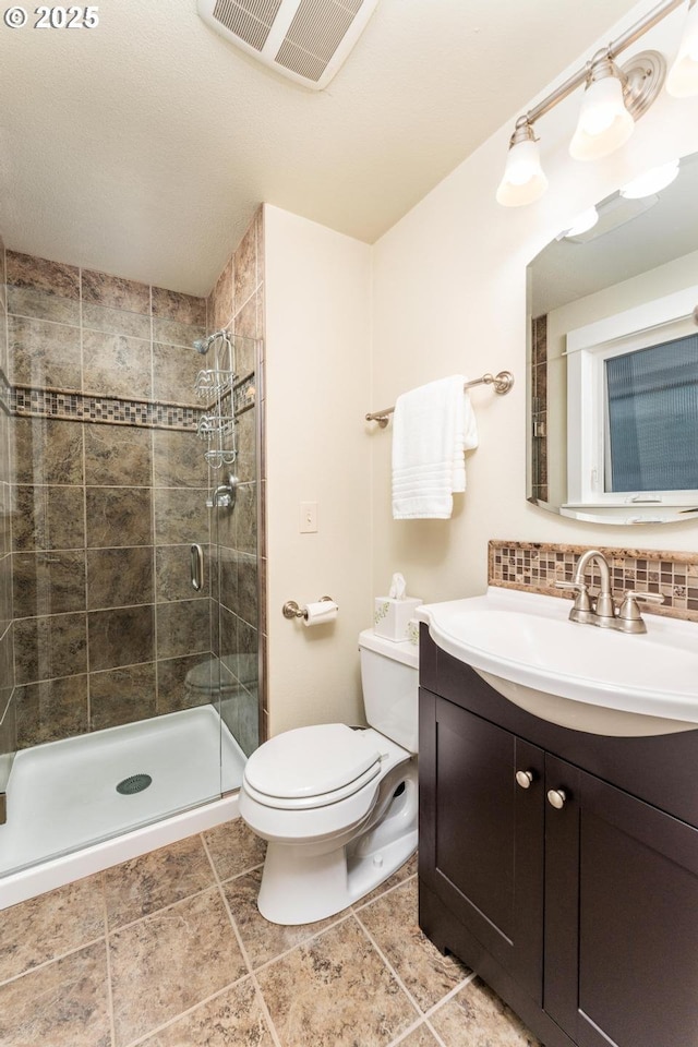 full bath with toilet, visible vents, a tile shower, and vanity