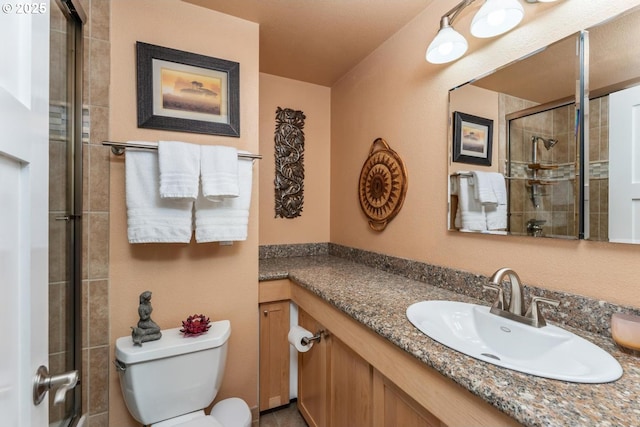 bathroom with toilet, a tile shower, and vanity