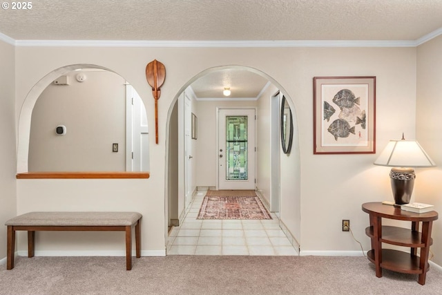 carpeted entrance foyer with crown molding, baseboards, arched walkways, and a textured ceiling