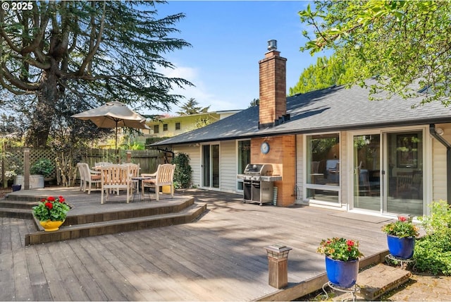 wooden deck with outdoor dining space, fence, and area for grilling
