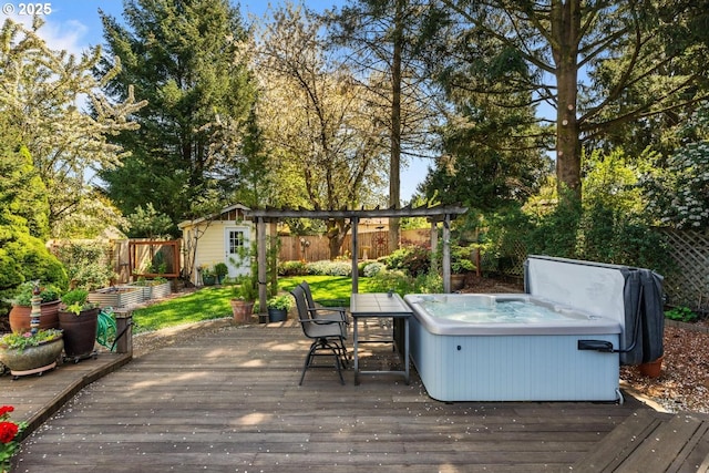 wooden deck with a hot tub, an outdoor structure, and a fenced backyard