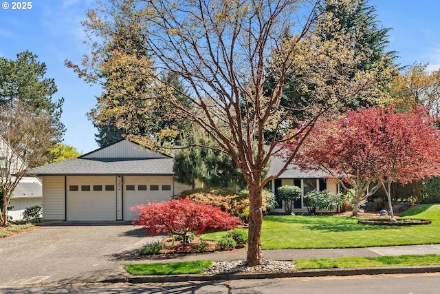 view of front facade featuring roof with shingles, a front yard, and a detached garage