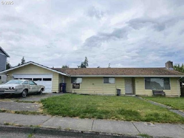 ranch-style home with a garage and a front lawn