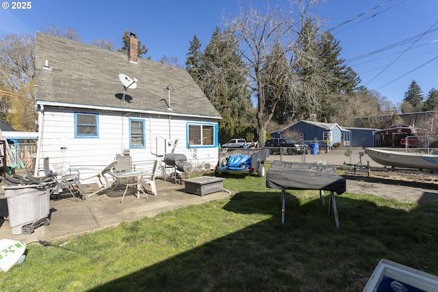 back of property with a patio area, a lawn, a chimney, and fence