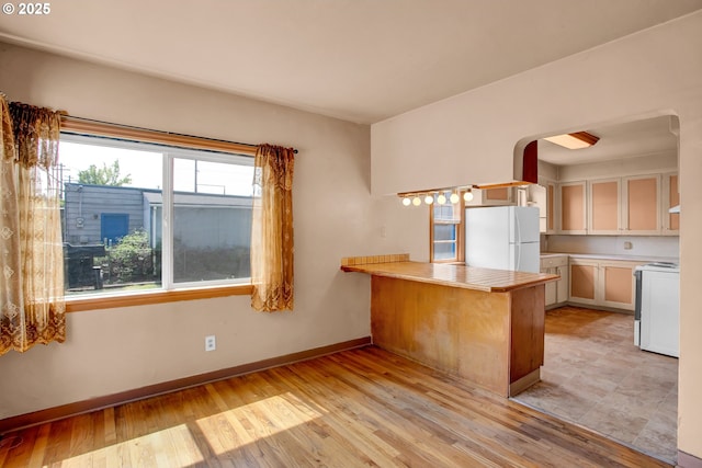 8935 SE Stanley Pl, Portland, OR 97206 - kitchen featuring stove, light wood-style flooring, freestanding refrigerator, a peninsula, and baseboards