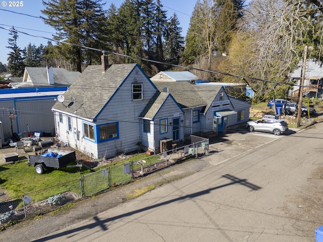 view of front of house featuring a fenced front yard, roof with shingles, and a chimney