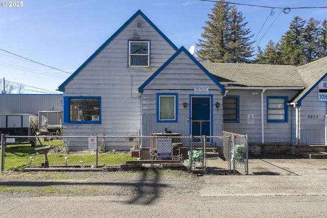 view of front of house with entry steps, roof with shingles, a fenced front yard, and a gate