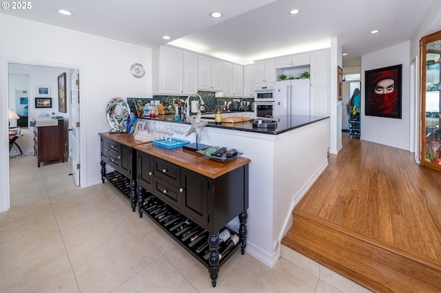 5952 SW Cupola Dr, South Beach, OR 97366 - kitchen with white appliances, white cabinets, decorative backsplash, dark countertops, and a peninsula
