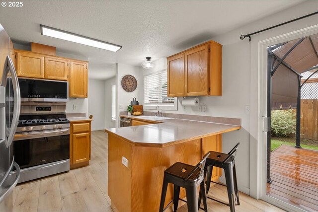 15314 NE 88th St, Vancouver, WA 98682 - kitchen featuring stainless steel appliances, a peninsula, light wood finished floors, a kitchen bar, and light countertops