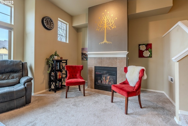 living area featuring carpet floors, a tile fireplace, and baseboards